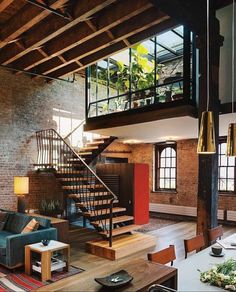 a living room filled with furniture and a spiral stair case next to a brick wall