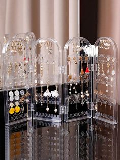 four clear acrylic jewelry displays on a black table with curtains in the background