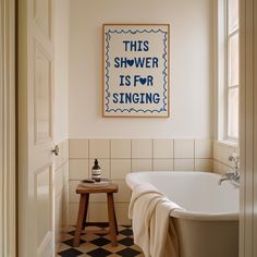 a white bath tub sitting next to a wooden stool under a painting on the wall