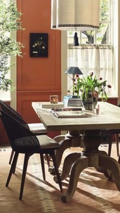 a dining room table with chairs around it and an orange wall in the back ground