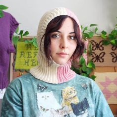 a woman wearing a sweater with cats on it and a knitted hat over her head