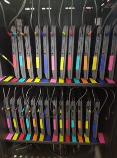 several rows of colorful binders with wires attached to them in a rack on the wall