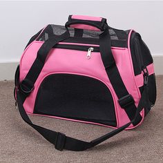 a pink and black dog carrier sitting on the floor