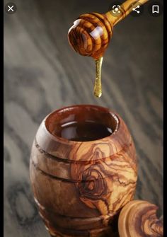 a honey dipper is being poured into a wooden jar