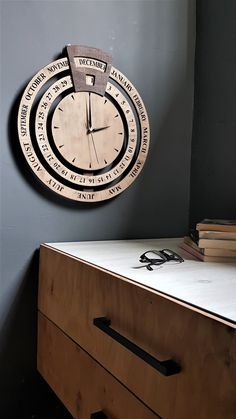 a clock mounted to the side of a wall next to a wooden dresser with glasses on it