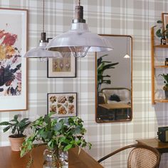 a dining room table with potted plants and pictures hanging on the wall behind it