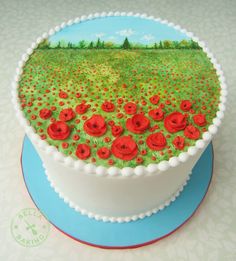 there is a cake decorated with red flowers on the top and green field in the background