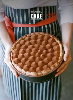 a person holding a cake in their hands with the words tiramu cake on it