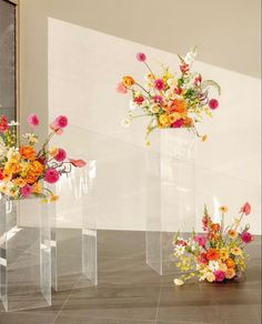 three clear vases with colorful flowers in them