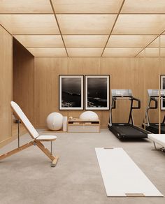 an empty gym with treadmills, exercise equipment and pictures on the wooden wall