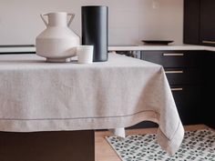 a white vase sitting on top of a table next to a black and white rug