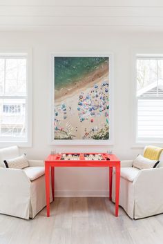 two white chairs and a red table in a room