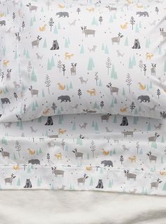 the bedding is made up with deer and moose print on it, along with white sheets