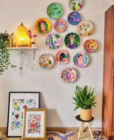 plates are arranged on the wall above a potted houseplant and framed pictures