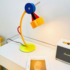 a yellow lamp sitting on top of a white table next to a book and radio