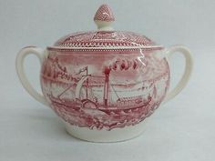 a red and white teapot with a boat on it's lid is shown