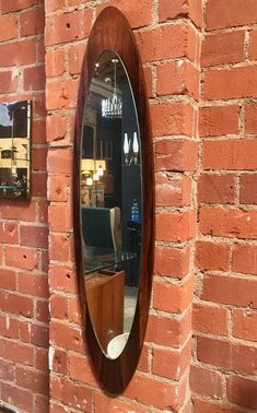 a round mirror mounted to the side of a brick wall