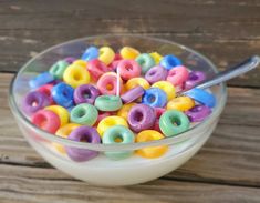 a glass bowl filled with lots of colorful donuts on top of a wooden table