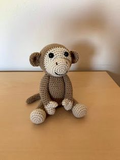 a crocheted monkey sitting on top of a wooden table