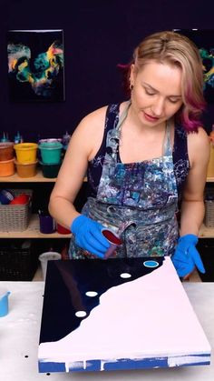 a woman in an apron and blue gloves working on a piece of art