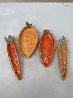 three ceramic carrots and one broccoli sitting on a counter top next to each other