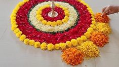 a person standing in front of a large flower arrangement on the floor with a candle