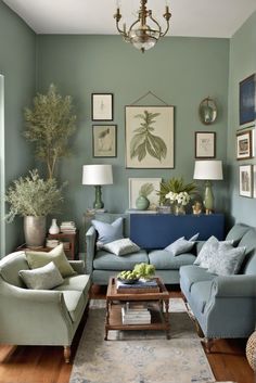 a living room with green walls and blue couches, coffee table, lamps and pictures on the wall