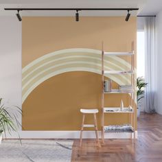 a room with a book shelf, plant and wall mural in the corner that has an abstract geometric design on it