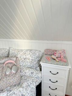 a white bed sitting under a wooden ceiling next to a night stand with two drawers