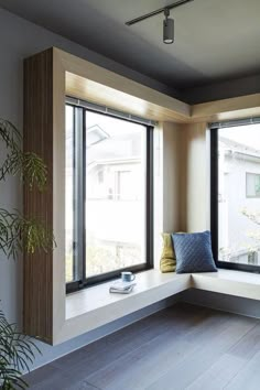 a window seat with pillows on it next to a potted plant