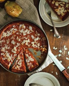 a pizza sitting on top of a wooden table next to plates and utensils