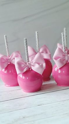 four pink candy apples with bows on them