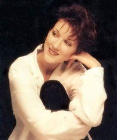 the woman is posing with her hands on her head and wearing a white coat over her shoulders