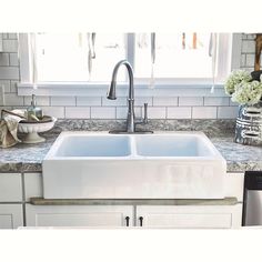 a white kitchen sink sitting under a window next to a faucet and dishwasher