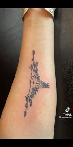 a woman's arm with a bird and flowers tattoo on it