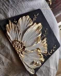 a black and gold tray with flowers on it sitting on top of a white sheet