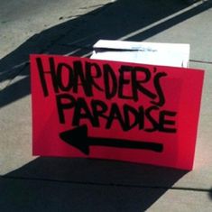 a red sign with the words hoarders paradise written on it and an arrow pointing up