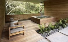 an outdoor hot tub on a wooden deck next to a chair and tree's