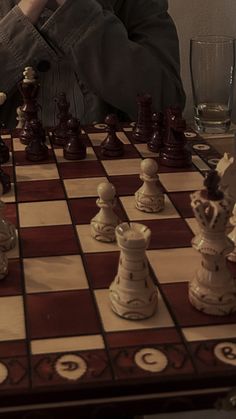 a man sitting at a chess board with his hand on the queen's head