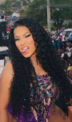 a woman with long black hair standing in front of a crowd at an outdoor event