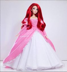 the doll is wearing a pink and white dress with long red hair, while she wears a tiara