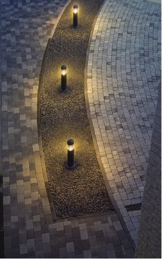 an aerial view of a walkway with lights on the sides and grass in the back ground