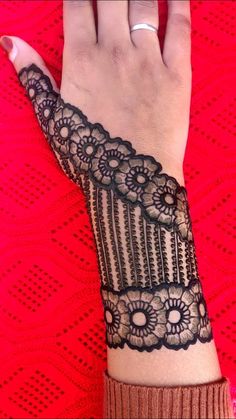 a woman's hand with a black lace design on the wrist and armband