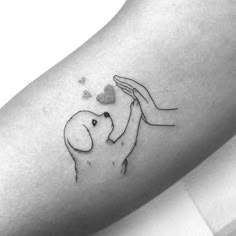 a small tattoo on the arm of a person holding a dog's paw with hearts