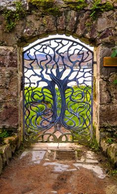 an iron gate with a tree in the center and vines growing out of it's sides