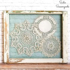 an old window frame with lace doily on it and a brick wall in the background