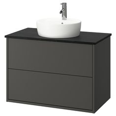 a white sink sitting on top of a gray cabinet next to a faucet