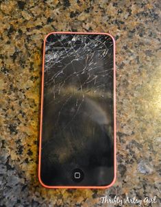 an iphone that has been cracked and is sitting on a counter top with the screen broken off