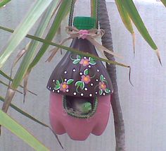 a pink birdhouse hanging from a palm tree with flowers on it's roof