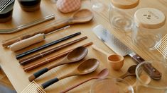 wooden utensils and spoons are on a table with wine glasses, cups, and other items